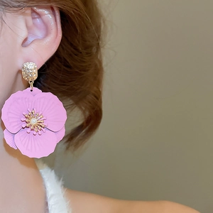 Gros plan d'un mannequin portant des boucles d'oreilles fleurs roses avec perle