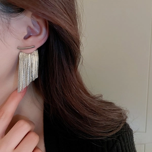 Close-up of silver long chain tassel earrings worn on model for a trendy metallic look