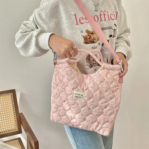 Detailed close-up of pink quilted crossbody bag with bunny and floral patterns