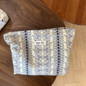 Flat lay of vintage floral cloth makeup bag with simple wish label on a wooden table