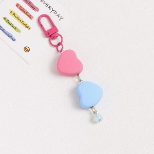 Close-up of pink and blue heart-shaped pendants with metallic chain for keychain decor