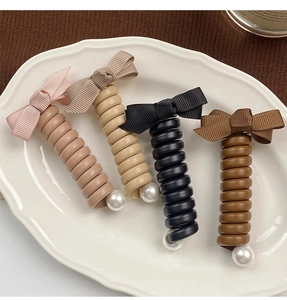 Détails d'élastiques à cheveux spirales avec nœuds et perles sur plat en céramique