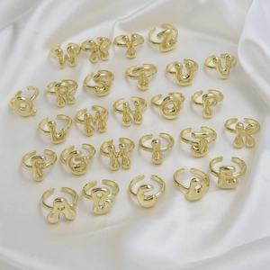 Set mit 26 verstellbaren 18k vergoldeten Bubble-Buchstabenringen auf weißem Seidenhintergrund