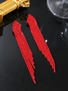 Macro shot of long red rhinestone tassel earrings on a sleek black reflective surface