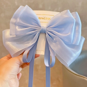 Detail of light blue organza oversized bow hair clip with shimmering fabric and long ribbons