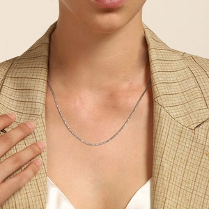 Detail shot of a slim silver snake chain necklace on a model wearing a blazer