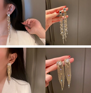 Detail of U-shape tassel earrings with pearls and crystals in high-end gold finish