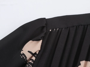Detailed view of the pleated front and abstract print on this black short sleeve dress
