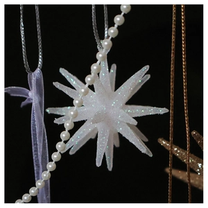 Close-up of sparkling white star ornament with silver sequins and hanging string