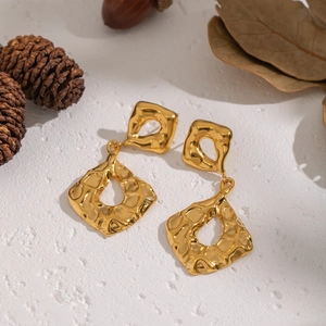 Minimalist gold geometric earrings with hammered texture on a natural textured background