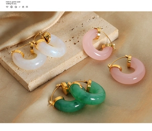 Detailed view of pearl white pink and green resin hoop earrings on champagne silk fabric
