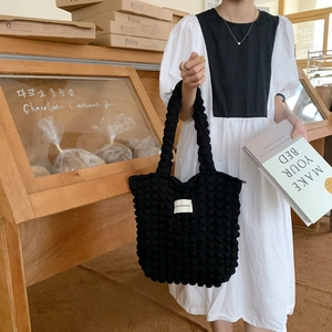 Dettaglio della trama della borsa tote nera in tessuto popcorn con logo bianco