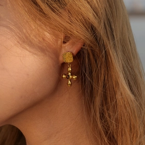 18k gold plated stainless steel cross earrings with tiger eye stone on a model