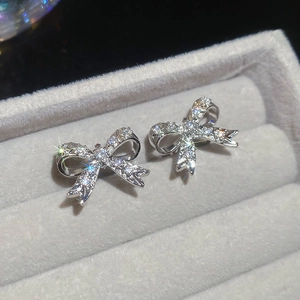 Dettaglio di un orecchino a fiocco in argento con zirconi su velluto grigio scuro