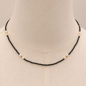 Détail du collier de perles noires facettées, perles baroques et accents dorés