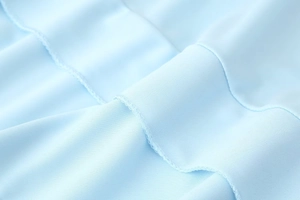 Close-up of light blue fabric texture and professional machine-stitched hem details