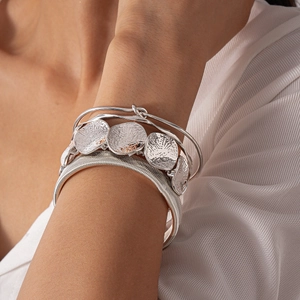 Close-up of bohemian silver bangle set featuring hammered disc details on female wrist