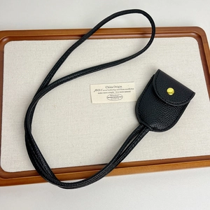 Détail de la cloche en cuir grainé noir avec bouton pression doré et cordon de cou