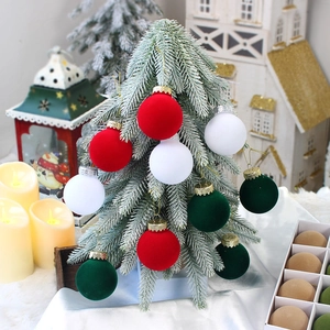 Geflokte kerstballen in rood, groen en wit aan boom met een geschenkverpakking