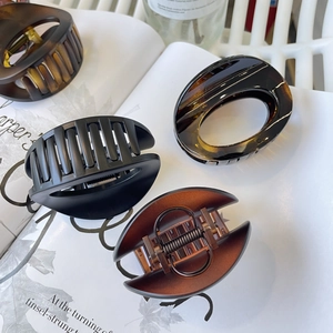 Detailed view of matte black and amber oval hair claws on white book pages