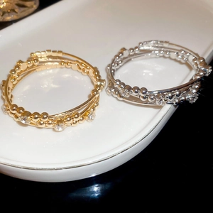Macro detail of multi-layered geometric bracelets with zircon stones and bead accents