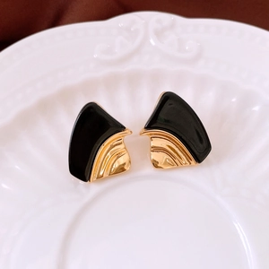 Détail de boucles d'oreilles géométriques noir et or avec des nervures en forme d'éventail