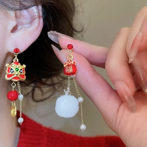 Close-up of Chinese New Year lion dance earrings with red enamel and plush details