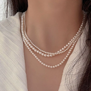 Detailed view of triple-layer pearl necklace on model showing elegant layering and drape