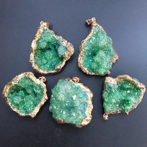 Macro shot of five green druzy geode pendants with gold plating on a black background