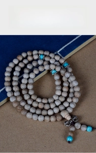 Macro detail of natural wood 108 prayer beads with turquoise and silver accents