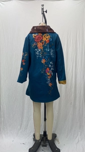 Detail of red and yellow floral embroidery on the back of a navy blue long-sleeve coat