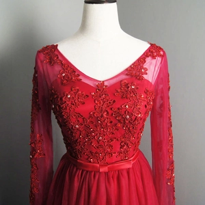 Detail of red evening dress featuring intricate lace appliques and sequin beaded V-neckline