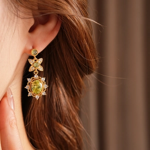 Gros plan de boucles d'oreilles vintage dorées avec pierres vert olive et halo diamanté