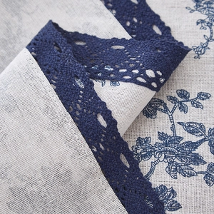 Close-up of beige linen table runner with blue floral print and crochet lace edging