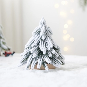 Mini flocked Christmas tree with snow effect on a wooden base with bokeh light background