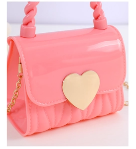 Detail of pink mini jelly bag with golden heart clasp and twisted top handle texture