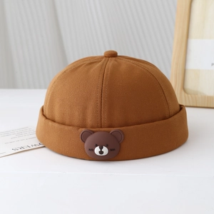 Détail du bonnet docker marron pour enfants avec écusson décoratif ours en peluche 3D