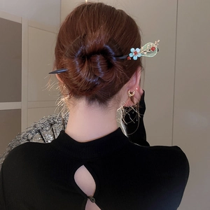 Detail of vintage flower hair stick with blue petals and gold leaves in a hair bun