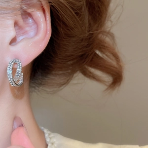 Close-up of sparkling double-layer silver earrings with zircon inlay on model's ear