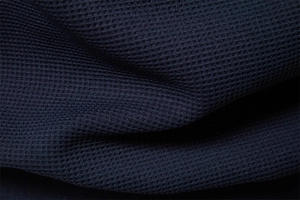 Macro view of dark navy waffle knit fabric texture showing high-quality honeycomb pattern