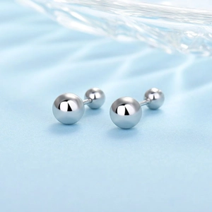 Detailed close-up of silver ball stud earrings with screw-back design on blue background