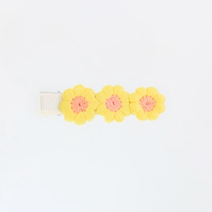 Detail of three yellow and orange embroidered crochet flowers on a fabric-covered hair clip