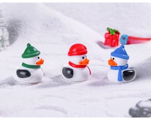 Three creative Christmas rubber ducks in winter hats on a snow background landscape