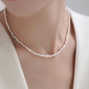 Close-up of elegant small white freshwater baroque pearl necklace worn on model neck