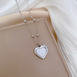 Detail of silver heart pendant with white shell inlay and crystal on beaded chain