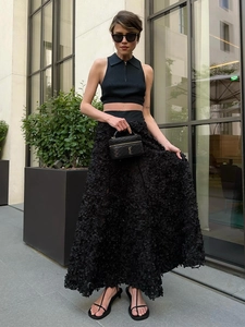 Detail shot of black maxi skirt featuring textured 3D floral petals and elegant modern design