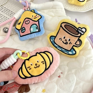 Detail of embroidered plush cartoon keychains featuring house and coffee cup designs