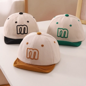 Detailed close-up of soft-brim baby baseball caps featuring letter m embroidery and cotton texture