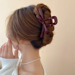 Close-up of a burgundy ribbon bow hair claw clip worn in a graceful bun hairstyle