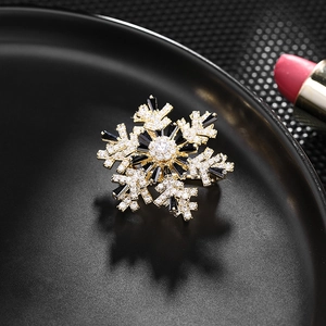 Macro shot of snowflake brooch with black and clear stones on a black plate